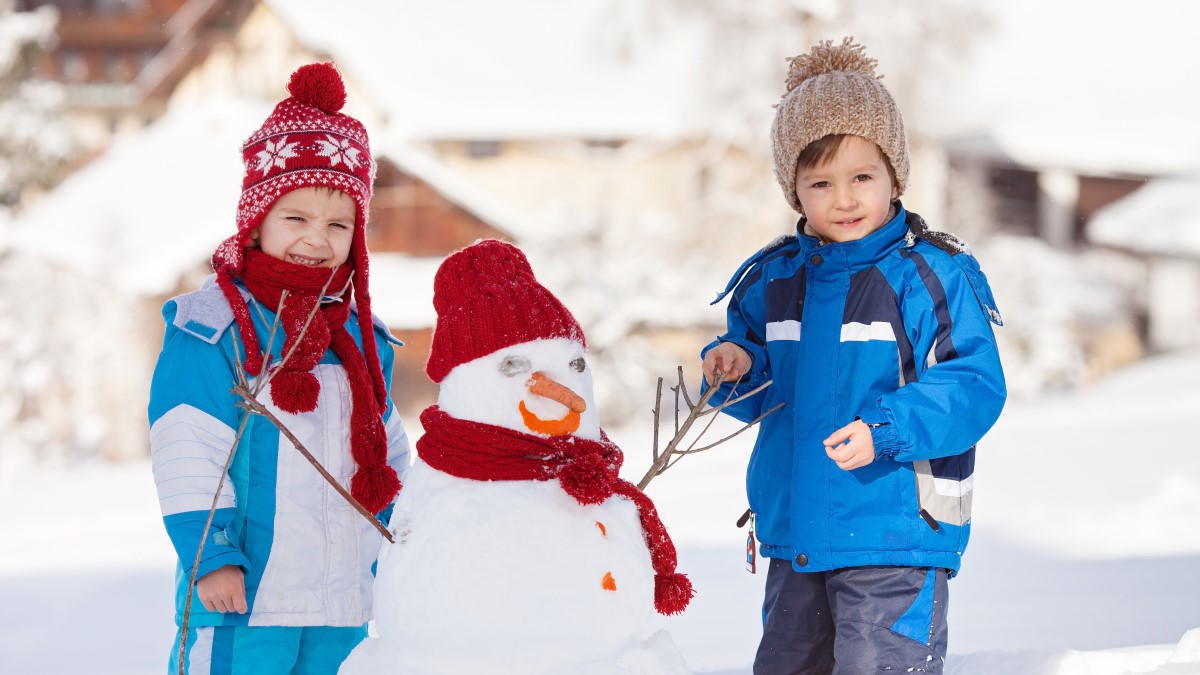 Young children in snowsuits playing outside in the snow.